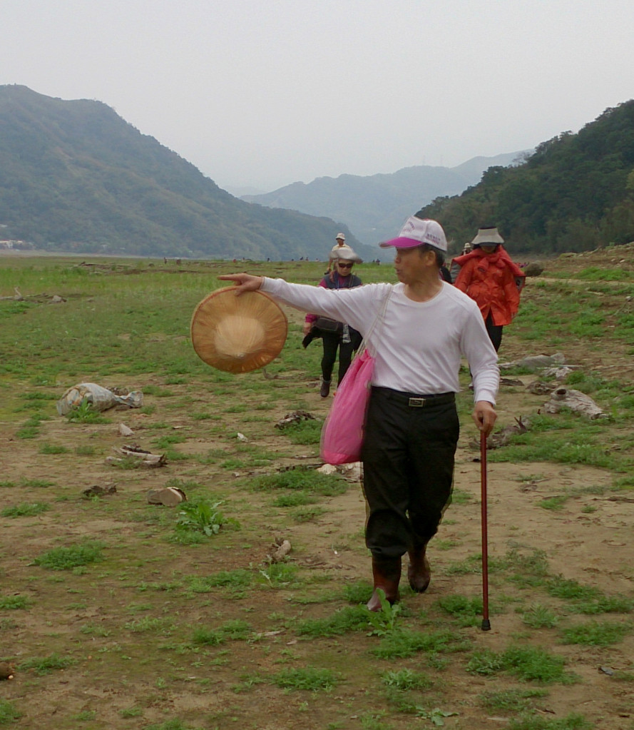 作者父親前往故居，途中娓娓向遊客訴說著昔日景致。（背景為枕頭山，圖片來源：湯松霖）