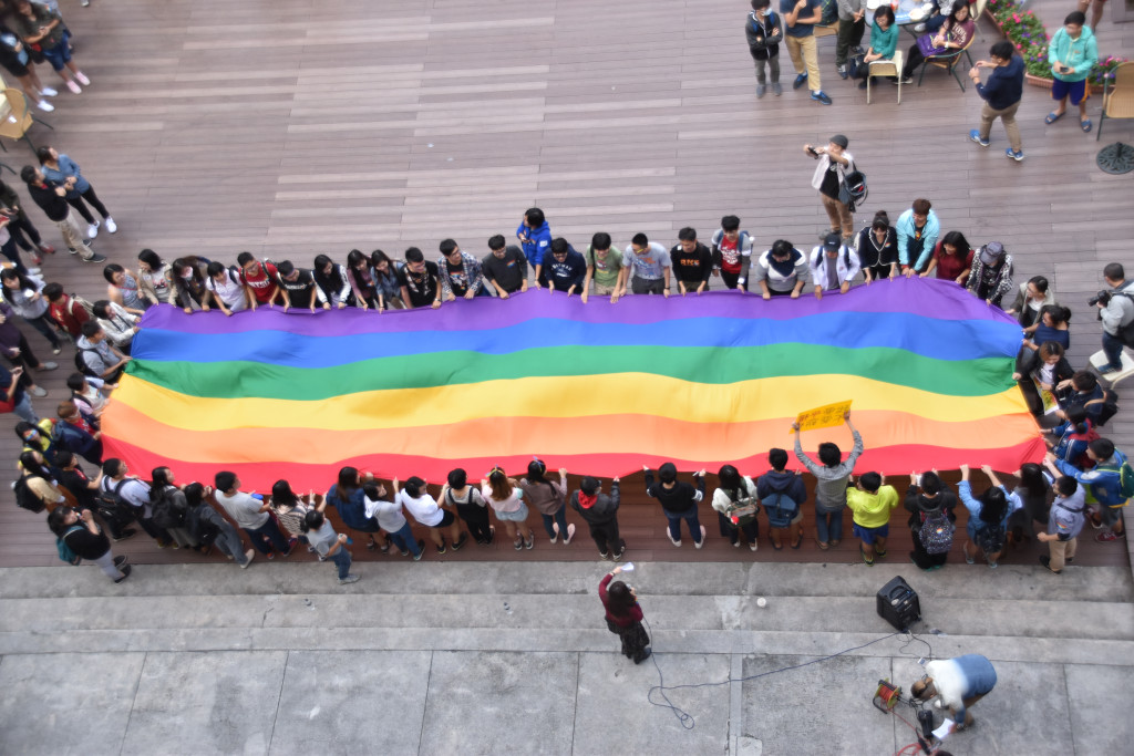 中山大學校內學生團體發起上百人在校園內一同高舉彩虹旗支持婚姻平權，並希望有更多大專院校一同加入，讓支持婚姻平權的校園活動遍地開花。圖／中山大學學生會提供