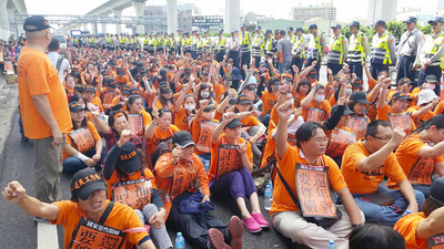 數百名前國道收費站失業收費員與家人,25日在中山高速公路中壢路段路肩上靜坐抗議,造成國道嚴重壅塞,並與警方對峙。最後在警力驅離下,被帶離國道。(中央社)