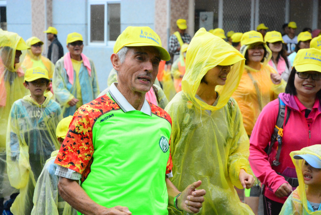 健走活動時下著小雨，劉一峰神父神采奕奕，帶領著大家暖身出發。（王志偉攝）