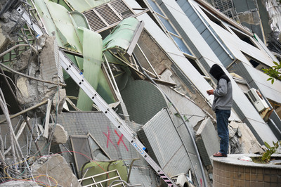 南台灣6日凌晨規模6.4的大地震，造成台南永康區維冠金龍大樓倒塌，警消搶救工作持續進行，在外等候的民眾則不停撥打電話，寄望受困親友還能接聽。(中央社提供)