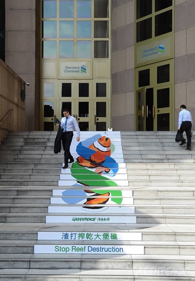 綠色和平發起行動,在渣打銀行門口張貼印有「渣打搾乾大堡礁」的布條,並向民眾發送傳單,揭發渣打銀行漠視煤採對環境的破壞。(圖片來源:綠色和平)