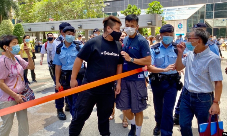 香港法院大樓外有支持及反對白衣人的市民在7月22日首宗7-21暴動案判刑後互相指罵，警方圍起封鎖線分隔。圖／擷自美國之音，湯惠芸攝