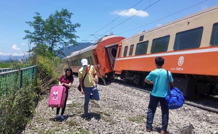 圖：台鐵莒光號列車今天中午在花蓮富里出軌，花東線多班列車，旅客拿著行李下車步行等待接駁車到來。（圖／台鐵提供）