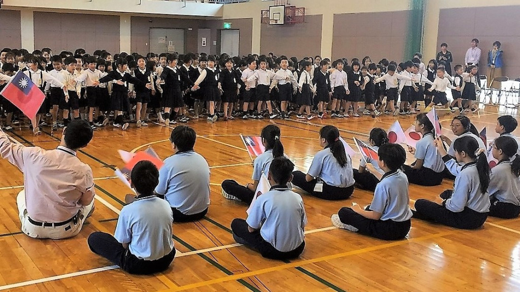 高市大同國小前往日本熊本與大津町室小學國際交流，精心規劃赴日「入班」進行一天的生活學習體驗，學童今持國旗「入班」室小學受到日方熱烈歡迎。(圖/大同國小)