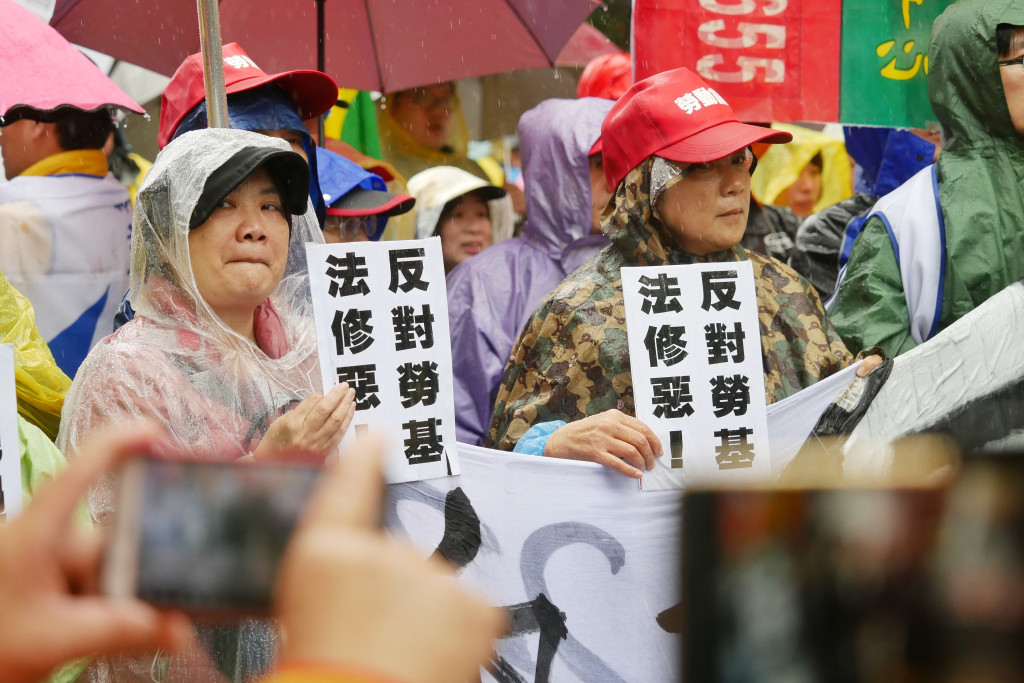 勞團在大雨中於立法院外高舉標語喊口號表達訴求，要求民進黨撤回勞基法修法草案，不要在今天臨時會強行通過三讀。圖／張家銘