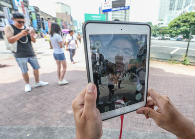 在全球爆紅的手機遊戲精靈寶可夢（Pokemon GO），6日終於在台灣區開放下載，許多人爭相下載，圖為光華商場周邊的民眾在街上體驗遊戲樂趣。圖／中央社