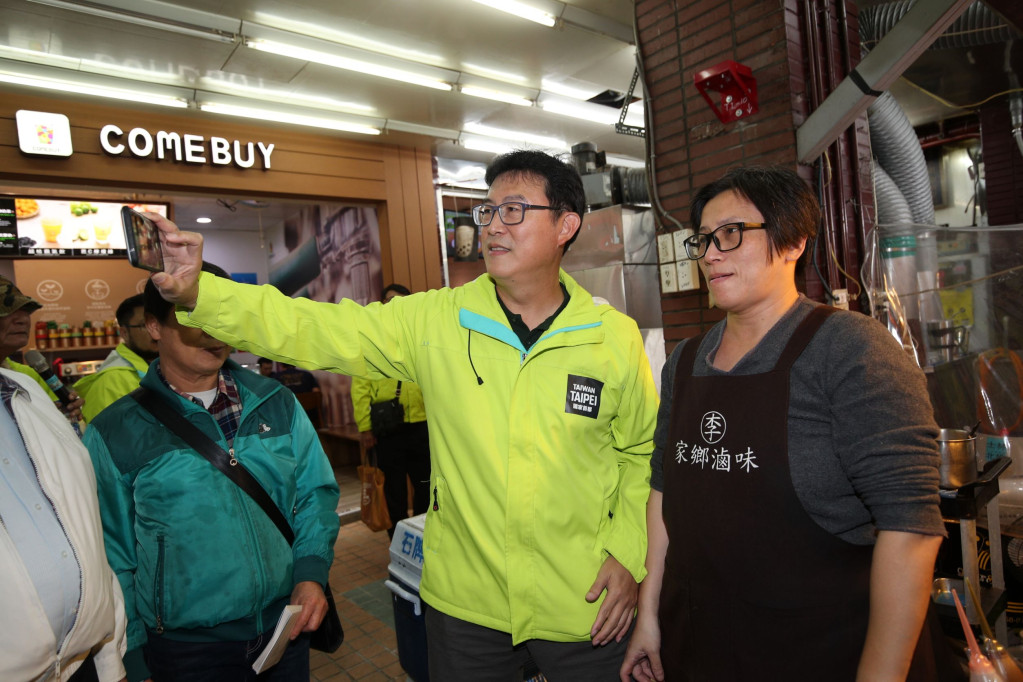 民進黨台北市長候選人姚文智今傍晚在士林北投區議員候選人謝維洲、陳賢蔚陪同下，至石牌商圈拜票，有熱情商家拿出手機與他自拍。圖／姚文智辦公室提供