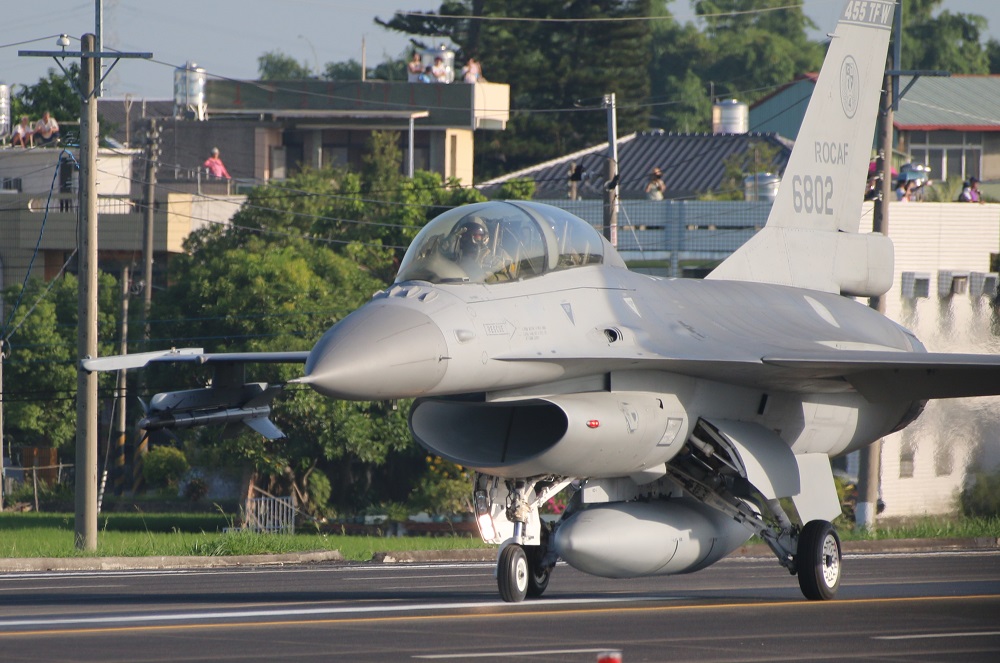軍方漢光演習，空軍飛官駕著F-16降落國道，帶領其他戰機行經媒體採訪區前，不忘行舉手禮致意，背後可見許多民眾站在屋頂觀看。（記者何豪毅攝）