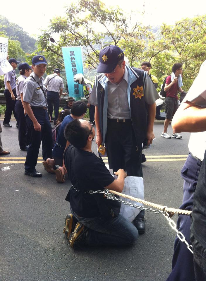 黑島青成員以鐵鍊綑身坐在路上當路障，遭警方以現行犯上銬逮捕。（圖取自黑島青臉書）