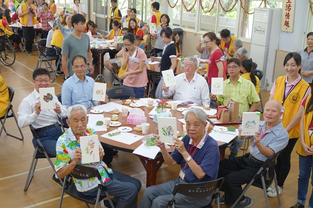 「水年伯」游錫堃率團到中市慰訪市立仁愛之家的長輩，並一齊作工藝，場面溫馨。（中市新聞局提供）