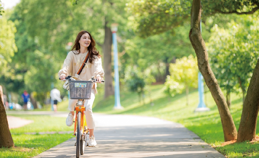 騎著YouBike在龍岡萬坪公園的綠蔭中漫遊，十分愜意。圖／陳培峯