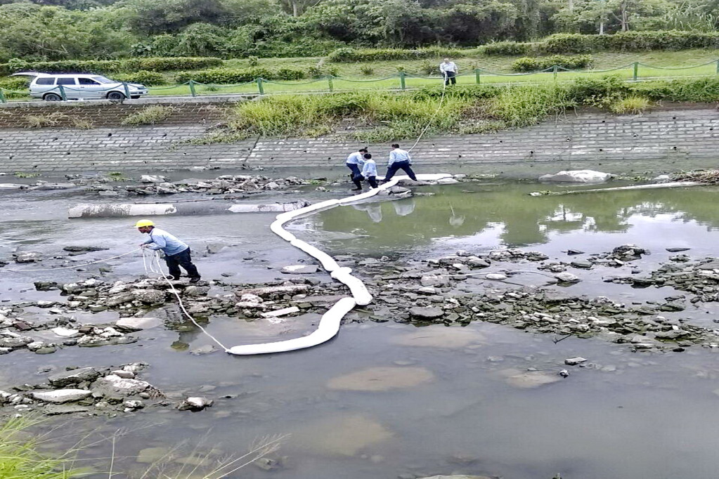 和桐化學公司因「正烷烴製程煤油貯槽液位計」故障，竟將防溢堤雨水排放口打開，致使煤油溢出流入後勁溪，環保局派員進行相關緊急作為並在後勁溪河段設置攔油索，由該公司人員同時清除油污。(圖/高市環保局)