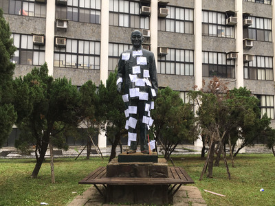輔仁大學校園蔣介石銅像,28日遭民眾與學生以砂輪機切割破壞,銅像拐杖遭鋸斷、左腳鋸出缺口。今天上午蔣介石銅像被貼滿二二八罹難者的資料。圖/中央社