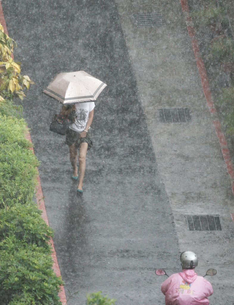 台北地區下午受天鴿颱風外圍環流影響，開始出現間歇性大雨，一位女性民眾在大雨中拉高裙子以免淋濕。圖/張良ㄧ