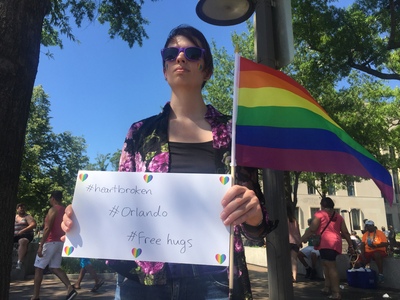 參與華府「同志驕傲月」活動支持者,手持海報為佛州奧蘭多同志夜店發生的槍擊案致哀,她也擁抱陌生路人,希望以更多的愛為美國社會療傷止痛。圖/中央社