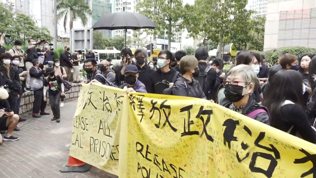 2021.3.1香港47人被控顛覆案，在西九裁判法院現場的聲援民眾拉起多幅釋放政治犯的布條。圖／擷自立場新聞影片