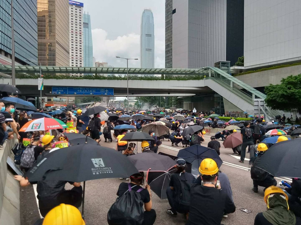 香港警8月31日傍晚向金鐘地區示威者施放催淚彈，示威者蹲下並舉傘掩護。圖／RTI