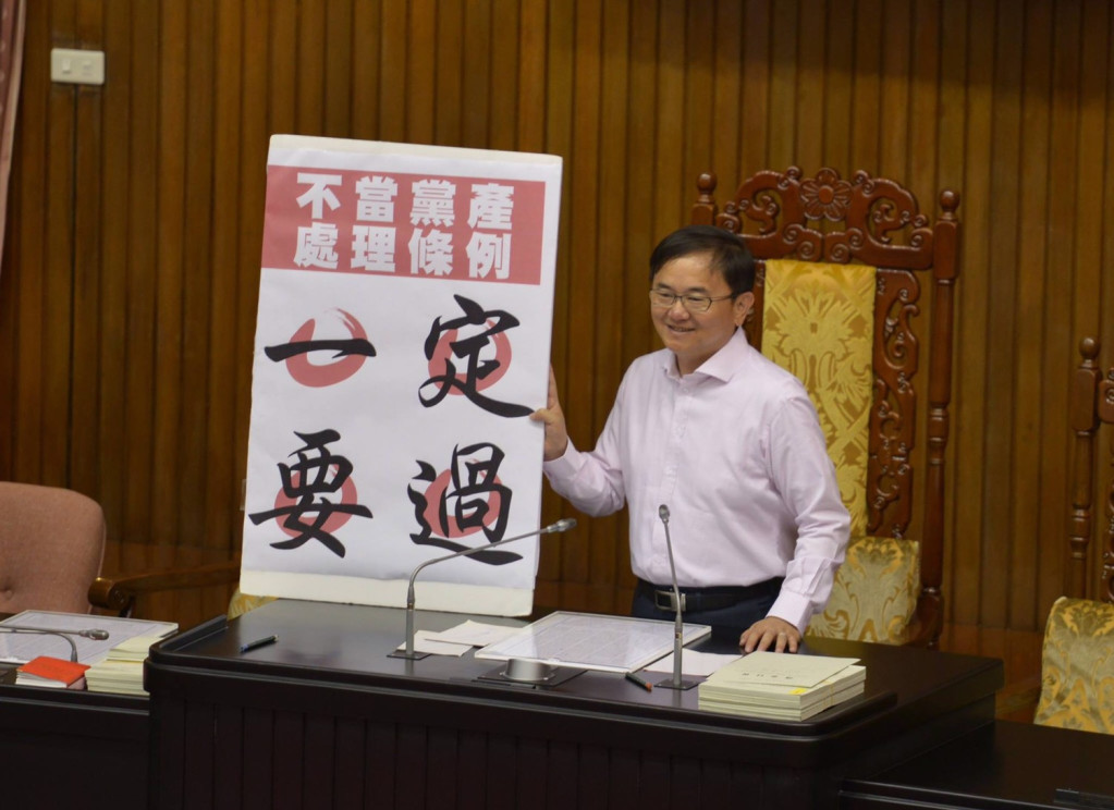 為了確保《黨產條例》議事順利進行，民進黨立委劉櫂豪在議場「捍衛」主席台，手持「一定要過」的牌子。圖／郭文宏。