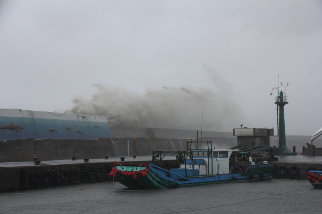 富岡漁港外堤的紅燈塔今早被發現被打入海中，下午豪大雨持續，大浪不時打上堤防激起十餘公尺浪花，可見海浪威力之大。（王志偉翻攝）