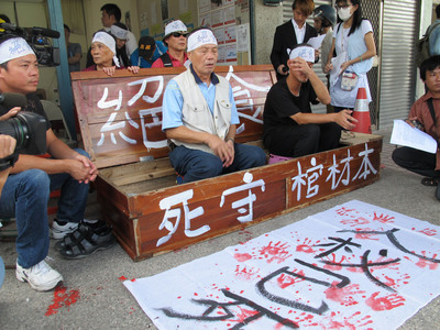 高雄市果菜市場拆遷案，自救會20餘人22日頭綁布條坐棺抗議，批評市長陳菊拒與人民辯論對話，發起「絕食護家園、護棺保人權」，揚言直到市府有回應為止。圖／中央社