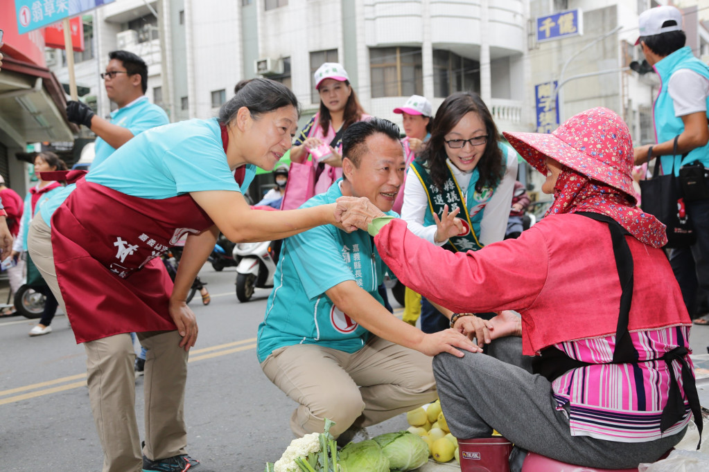 民進黨嘉義縣長候選人翁章梁今(4)日前往民雄菜市場拜票，蹲在攤販旁關心販賣狀況，向鄉親說明自己的政見。圖／翁章梁競選團隊提供