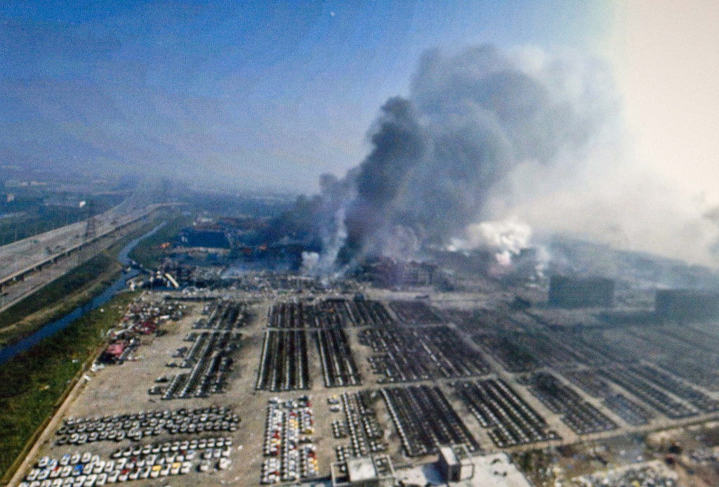 大爆炸隔天的13日下午，火災現場持續冒出濃煙。（圖片翻攝自Yue Yuewei/ Xinhua, via Associated Press）