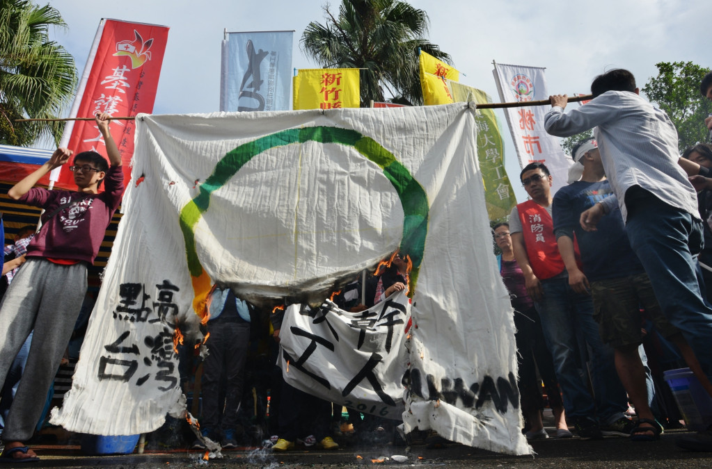 勞團跟絕食勞工代表燒毀「點亮台灣」的旗幟，批評民進黨選前說要點亮台灣，選後變成「點亮台灣資方」，強行砍七天假犧牲勞工權益。圖／郭文宏。