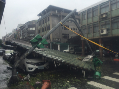 蘇迪勒颱風帶來強風豪雨，北市民族東路跟龍江路口旁邊的違建屋頂因強勁風勢遭吹落，壓壞旁邊路燈與汽車。（中央社）