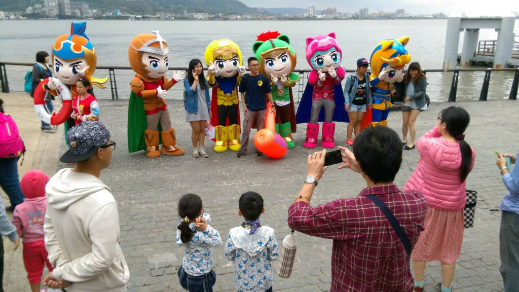 新北市消防局「平安六小福」人氣吉祥物全員出動，在淡水河邊踩街宣導防災，吸引不少民眾駐足拍照。（新北市消防局三大隊提供）