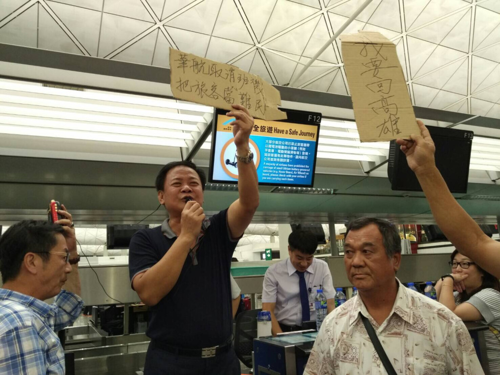 國民黨屏東縣議員張榮志在香港機場，舉「華航班機取消，把旅客當難民」標語向華航抗議。圖／朱高德提供