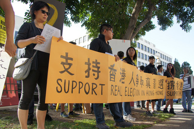 上百名在洛杉磯的香港僑胞28日（當地時間）聚集在當地中國領事館前，穿黑衣佩戴黃絲帶，表達對香港占中行動爭取真普選的支持。（中央社）