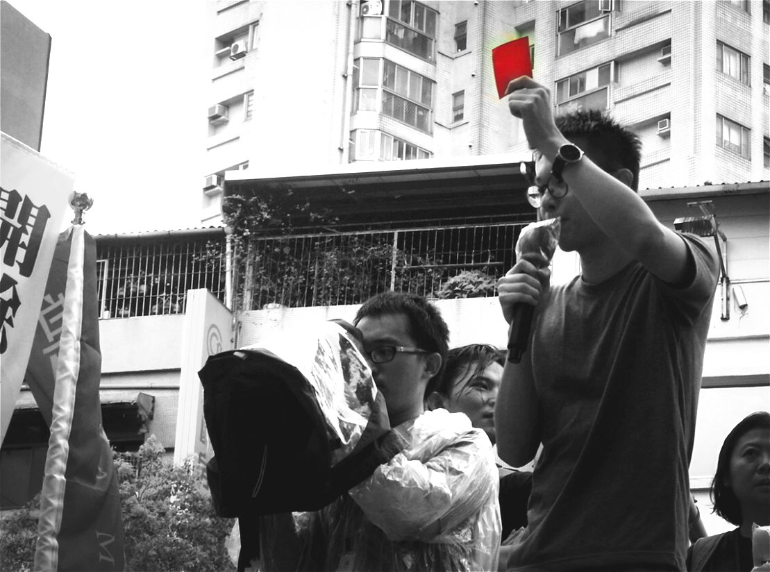 林飛帆舉著標準尺寸的紅牌，號召民眾周三下午1點半，帶著自製的紅牌到「王張會」現場舉牌說不！記者陳淑貞攝
