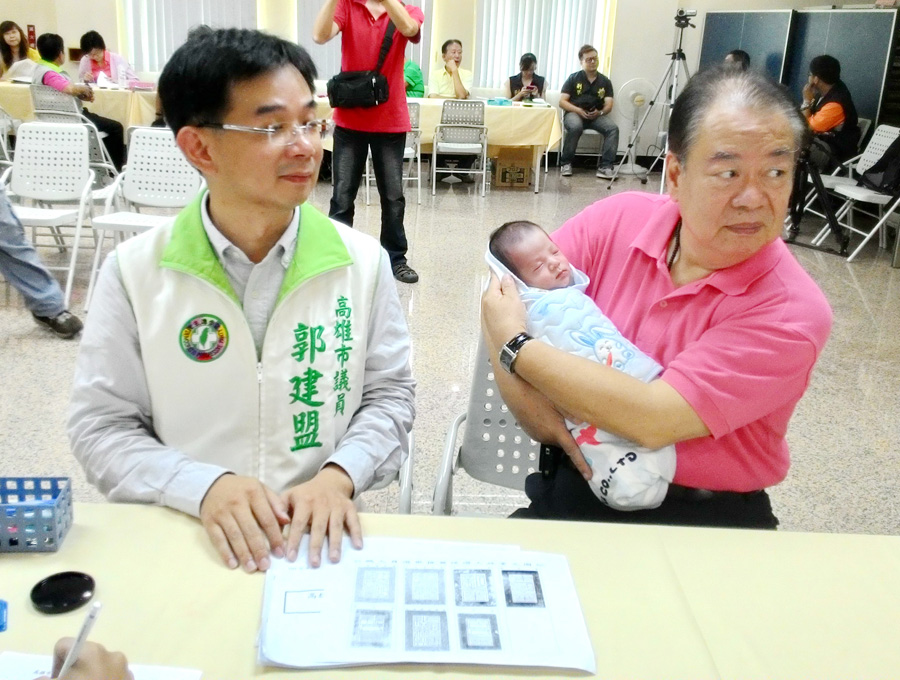 肉粽歌王郭金發抱孫，為兒子郭建盟登記參選高市議員助陣。（記者陳俊廷攝）