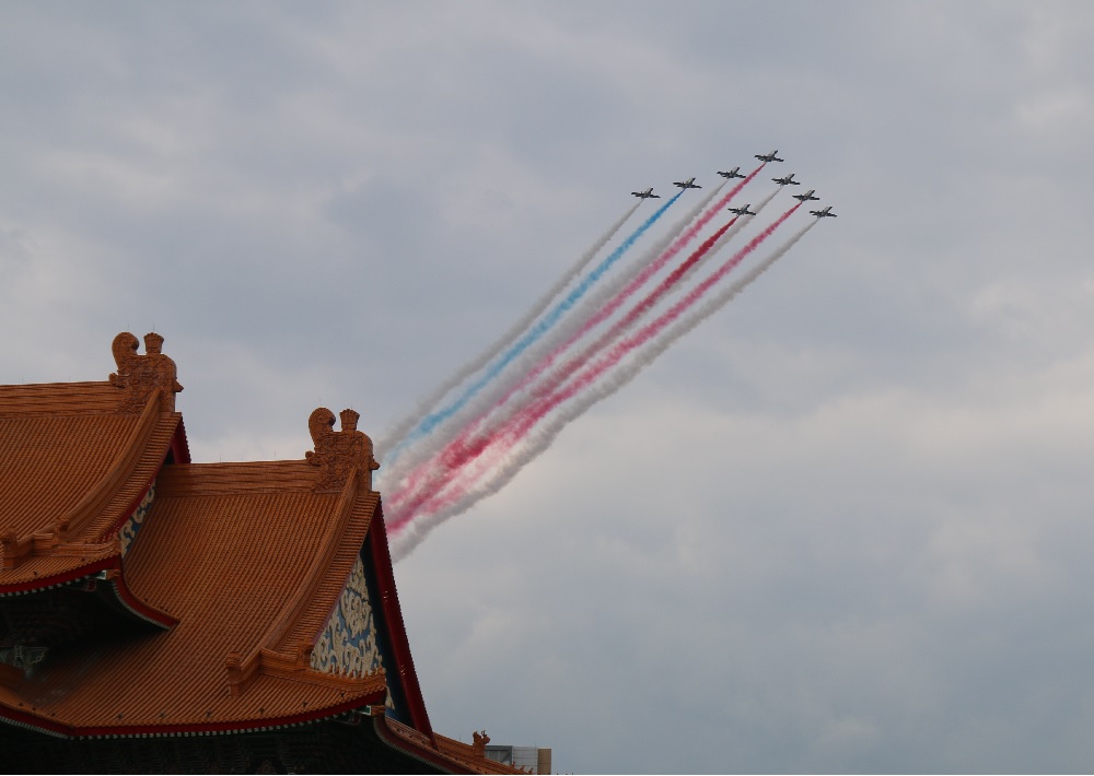 空軍雷虎小組今天下午預演國慶空中分列式，機尾噴出紅白藍三色煙霧，讓不少路人為之驚喜。圖左下角為台北國家音樂廳。（記者何豪毅攝）