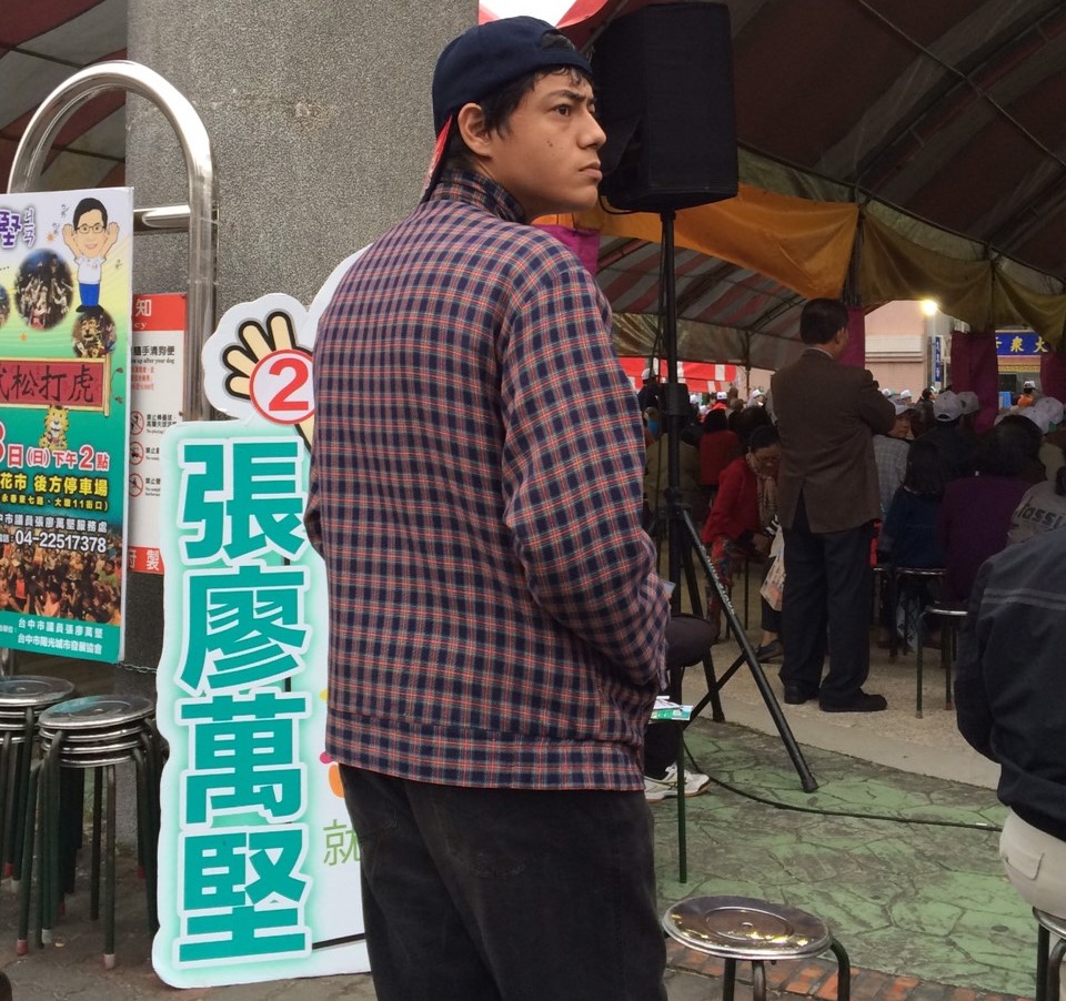 昨(26)日下午民進黨立委候選人張廖萬堅於台中市文心路家樂福旁舉行造勢活動,眼尖的網友發現一個熟悉的面孔,拍照回去比對新聞畫面後,發現是蔣萬安的堂弟─蔣友青。(翻攝自PTT八卦版)