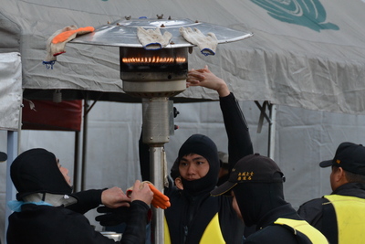 復興航空班機墜入基隆河空難，9日搜尋邁入第6天，搜救單位持續出動船艇及人員，搜索3名失蹤者。適逢寒流來襲，潛水與搜救人員烤火取暖。(中央社)