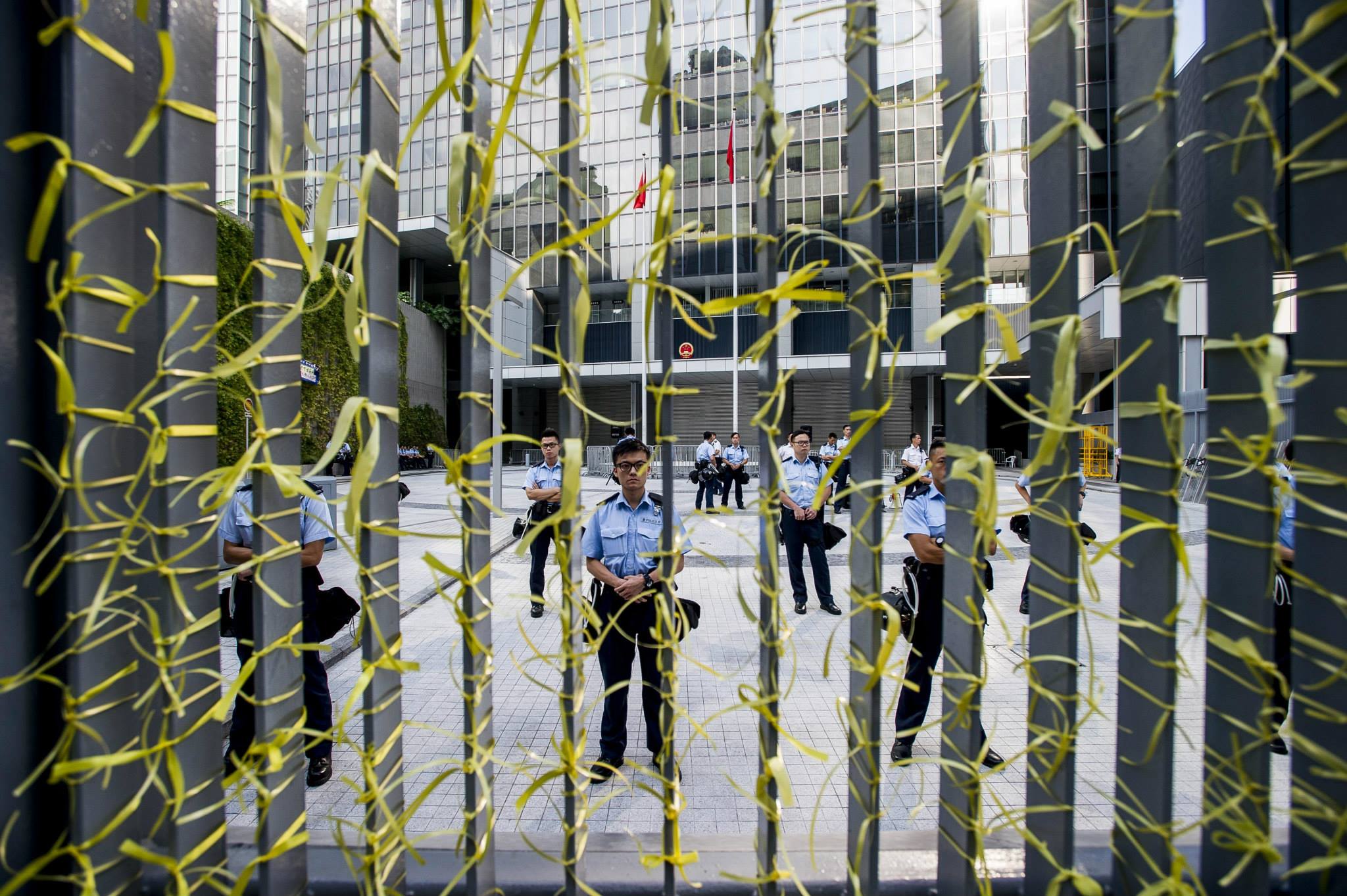 占中，黃絲帶也成為這場抗爭的象徵。圖為一處警方把守的路口，民眾在鐵拒馬繫上大量黃絲帶。（翻攝自香港獨立媒體網）