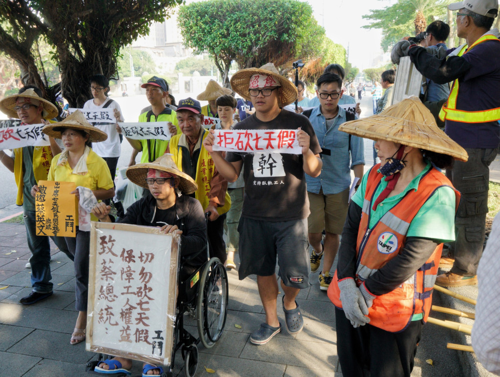 工鬥成員下午步行到總統府表達「拒砍七天假」訴求時，北市公園路燈管理處的一位工作人員停下手邊工作，看看他們的訴求。圖／張良一