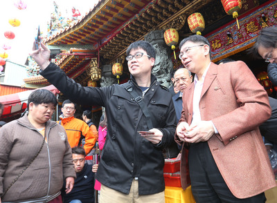 台北市長柯文哲(右)20日大年初二前往松山慈祐宮上香祈福,並發送招財福袋,吸引市民排隊領取。(中央社)