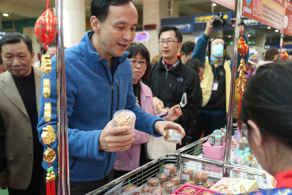 新北市長朱立倫（中）對跳樓輕生的違建屋主表示遺憾，但對公權力拆違建立場不變。圖為朱上午主持喜憨兒庇護工場年貨大街記者會後，前往購買食品分送記者。（記者何豪毅攝）20150123