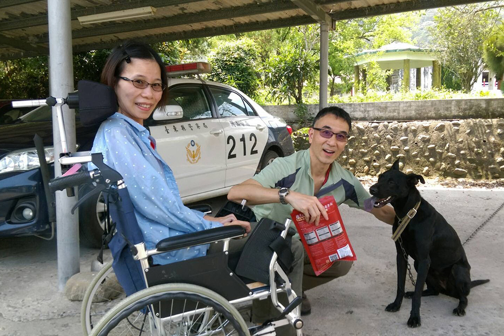 台東關山警分局收養流浪犬故事傳到國外，來自香港九龍的黃姓夫妻與「鼓勵」相見歡，坐輪椅的黃妻心情開懷。（圖片警方提供）